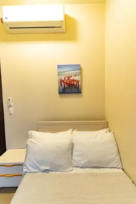 a bedroom with a bed with white pillows and a painting at 3BR Modern Uptown Parksuites BGC with bathtub in Manila