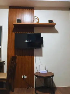a room with a tv on a wall with a table at Modern Style and Family Friendly in Manila