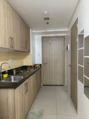 a kitchen with wooden cabinets and a sink and a door at Shore by Metro Staycation in Manila