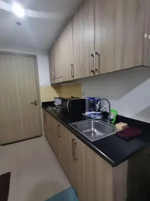 a kitchen with a sink and wooden cabinets at Shore by Metro Staycation in Manila