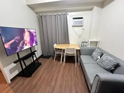 a living room with a couch and a table with a flat screen tv at Emmanuel's Lair Prisma Residences in Manila