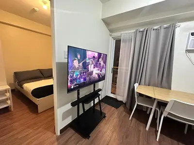 a small room with a bed and a flat screen tv at Emmanuel's Lair Prisma Residences in Manila