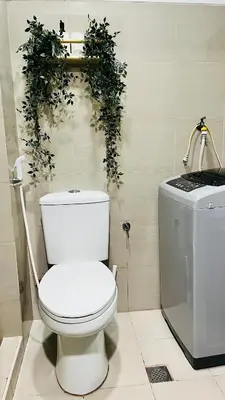 a white toilet in a bathroom with a plant on the wall at Direct Access to pool Bedroom in Manila