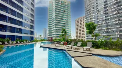 a swimming pool with lounge chairs and some buildings at Air Residences with 500Mbps Wifi in Manila
