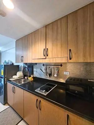 a kitchen with wooden cabinets and a black counter top at Sabrina Staycaytion in Manila