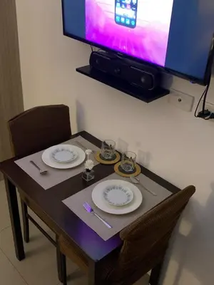 a table with two plates and a tv on a wall at Bay stays at shore residence in Manila
