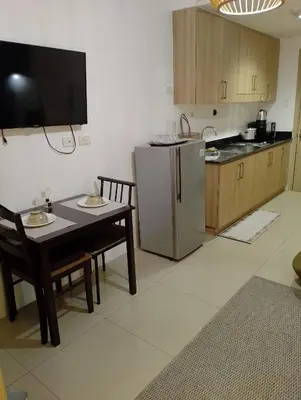 a kitchen with a table and a stainless steel refrigerator at Bay stays at shore residence in Manila