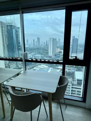 a white table and chairs in a room with a window at Condo Roughly 30 mins from NAIA with view of Greenhills in Manila