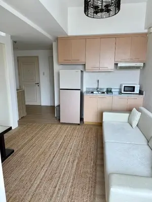 a living room with a couch and a kitchen at Condo Roughly 30 mins from NAIA with view of Greenhills in Manila