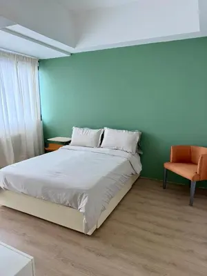 a bedroom with a bed and an orange chair at Condo Roughly 30 mins from NAIA with view of Greenhills in Manila