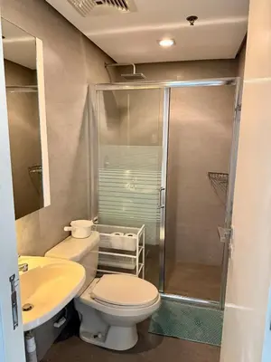 a bathroom with a shower and a toilet and a sink at Condo Roughly 30 mins from NAIA with view of Greenhills in Manila