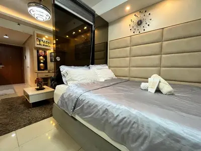 a bedroom with a large bed and a clock on the wall at EaseStay by Bren in Shell Residences MOA in Manila