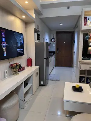a kitchen with a refrigerator and a tv on the wall at EaseStay by Bren in Shell Residences MOA in Manila