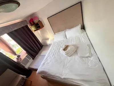 a small bedroom with a white bed with a window at Pahingahan in Cainta