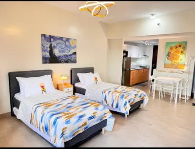 a bedroom with two beds and a kitchen with a table at Manhattan's Place in Manila