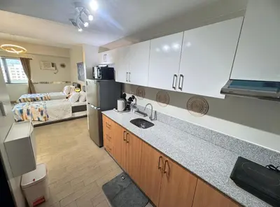 a kitchen with a sink and a room with a bed at Manhattan's Place in Manila