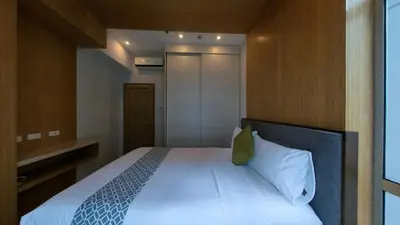 a bedroom with a white bed with a green pillow at Full-Serviced Residential Apartment in Blue Sapphire, BGC in Manila