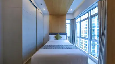 a bedroom with a bed and a large window at Full-Serviced Residential Apartment in Blue Sapphire, BGC in Manila