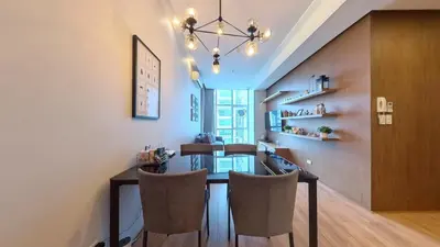 a dining room with a table and chairs and a chandelier at Full-Serviced Residential Apartment in Blue Sapphire, BGC in Manila