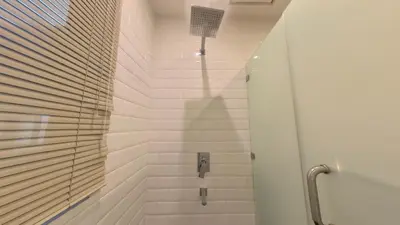 a white bathroom with a shower and a toilet at Full-Serviced Residential Apartment in Blue Sapphire, BGC in Manila