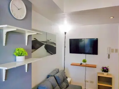 a living room with a couch and a clock on the wall at Azure Condo by arlene in Manila