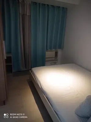 a bed in a small room with blue curtains at Azure place by arlene in Manila