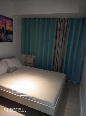 a bed in a bedroom with blue curtains at Azure place by arlene in Manila