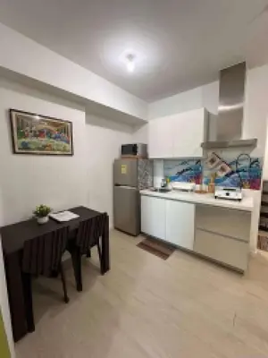 a kitchen with a table and a kitchen with a refrigerator at Azure Urban Resort by Tallia & Tiffany in Manila