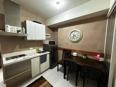 a kitchen with a table and a clock on the wall at Azure Urban Resort by Tallia & Tiffany in Manila