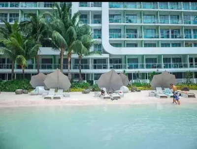 a beach with chairs and umbrellas in front of a building at Azure Urban Resort by Tallia & Tiffany in Manila