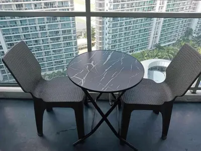 a glass table and two chairs in front of a window at Azure Urban Resort by Tallia & Tiffany in Manila