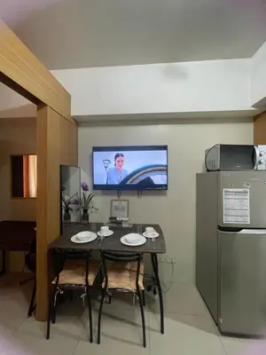 a dining room with a table and a television on the wall at 1bedroom Pool view 1441 shell residence with balcony in Manila