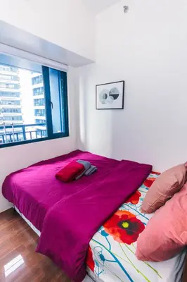 a bedroom with a bed with a pink blanket and a window at Air Dream Den Good Vibes Makati Gym Swim Park Superfast Internet 3870 in Manila