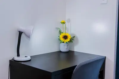 a desk with a lamp and a vase with a sunflower on it at Air Dream Den Good Vibes Makati Gym Swim Park Superfast Internet 3870 in Manila