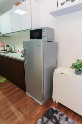 a kitchen with a refrigerator with a microwave on top at Air Dream Den Good Vibes Makati Gym Swim Park Superfast Internet 3870 in Manila