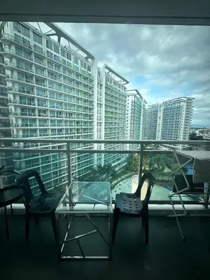 a balcony with two chairs and a glass table at Beach Condo at Azure Urban Resort with SmartTV in Manila