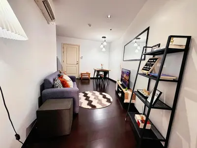 a living room with a couch and a book shelf at The Gramercy Residences NEW Sleek 1BR Suite, 600mbps Wifi, Netflix & FREE Amenities in Manila