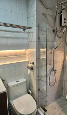 a bathroom with a toilet and a glass shower at Cozy Two-Bedroom Suite, Coast Residences, Pasay in Manila