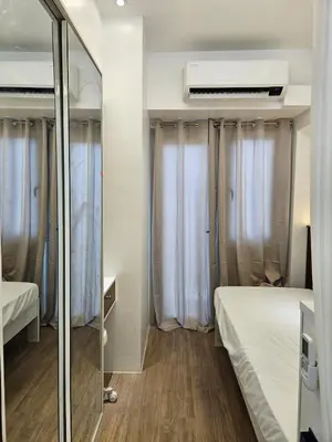 a small room with two beds and a mirror at Cozy Two-Bedroom Suite, Coast Residences, Pasay in Manila