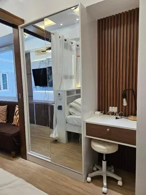 a room with a desk and a bed and a mirror at Cozy Two-Bedroom Suite, Coast Residences, Pasay in Manila
