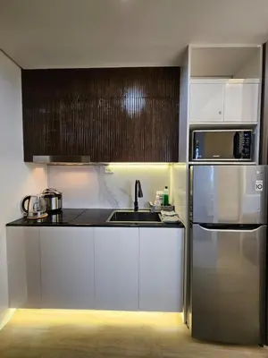a kitchen with white cabinets and a stainless steel refrigerator at Cozy Two-Bedroom Suite, Coast Residences, Pasay in Manila