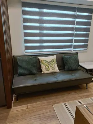 a couch with two pillows on it in a living room at Cozy Two-Bedroom Suite, Coast Residences, Pasay in Manila