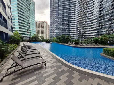 a swimming pool with lounge chairs and tall buildings at Air Residences Luxury Condo with Balcony Netflix Wifi in Manila