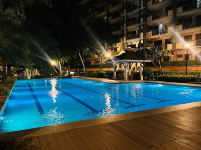 a large blue swimming pool with a gazebo at night at Acacia Estates' The Getaway Taguig, Evergreen in Manila