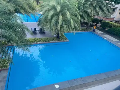 an overhead view of a large blue swimming pool with palm trees at Acacia Estates' The Getaway Taguig, Evergreen in Manila