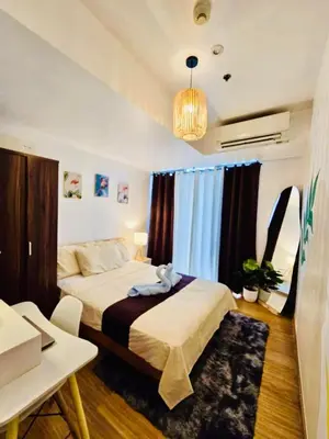 a bedroom with a bed and a table and a room at Azure staycation by Marco in Manila