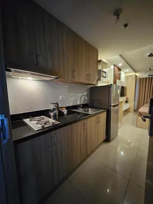 a kitchen with wooden cabinets and a stainless steel refrigerator at Soleil Suite 10 mins to SM Moa, Pasay - 2 beds in Manila
