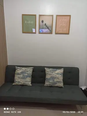 a couch in a living room with three pictures on the wall at Shore 2 Residence Tower 3 in Manila