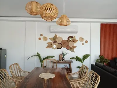 a dining room with a wooden table and rattan chairs at tierra de segundo in Binangonan
