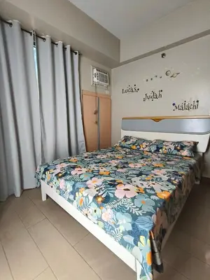 a bedroom with a bed with a floral bedspread at LDN Secret 1BR across NAIA Terminal 3 in Manila